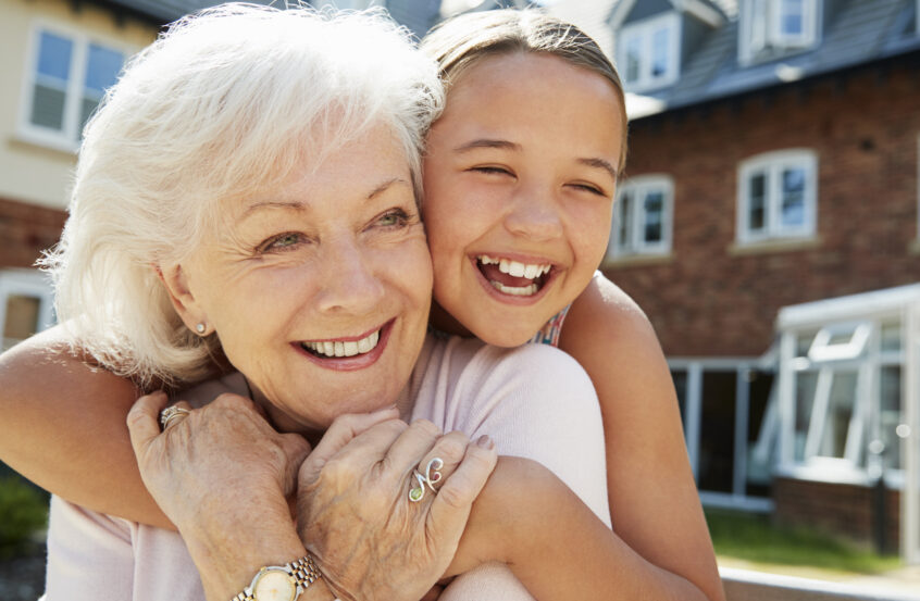 Granddaughter Hugging Grandmother on Bench During Visit to Retirement Home
